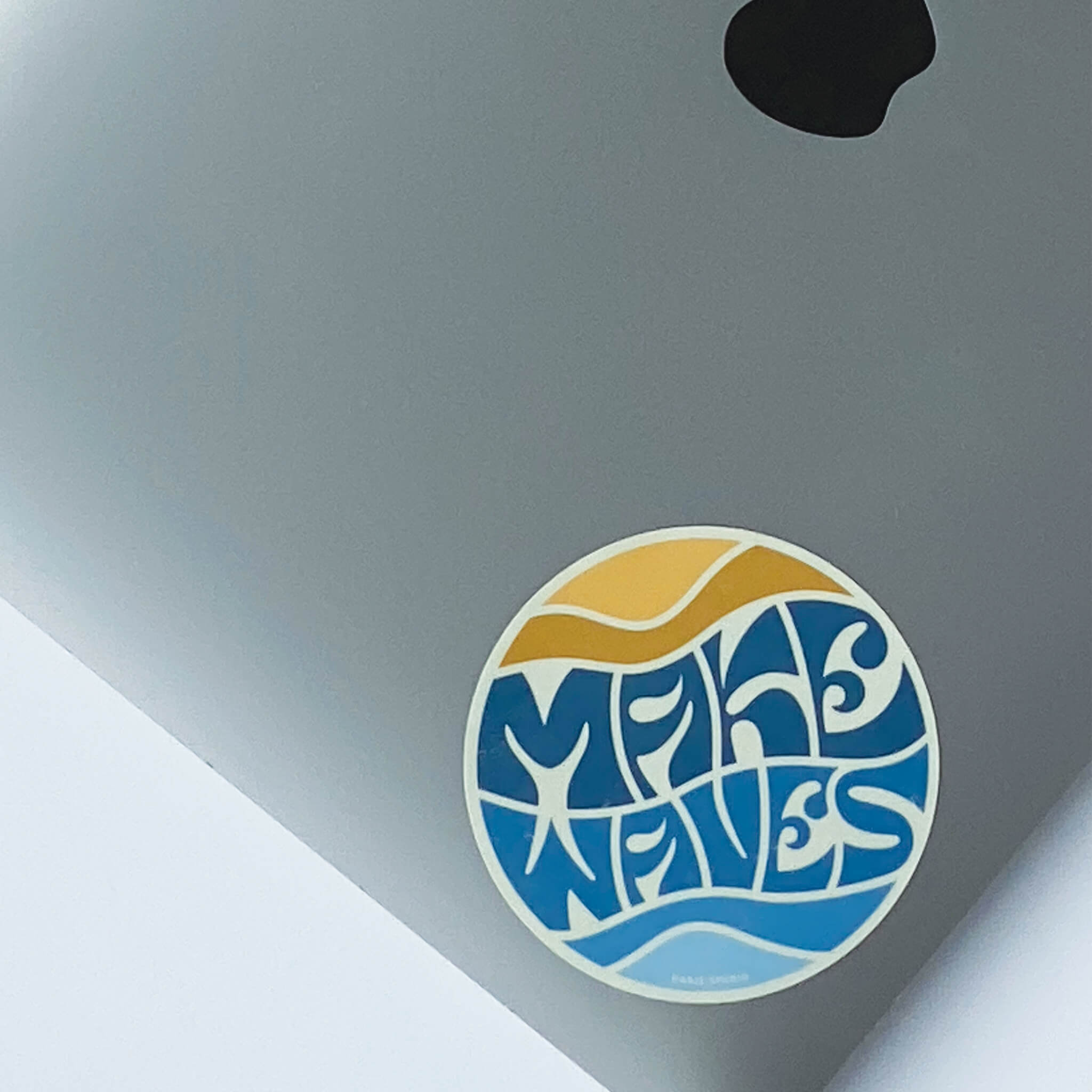 Circular 'make waves' sticker in yellow and blue on laptop